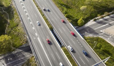 Vue aérienne d’une autoroute avec plusieurs voitures circulant sur différentes voies, illustrant le respect des distances de sécurité entre les véhicules.