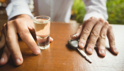 Un conducteur hésite entre un verre d’alcool et ses clés de voiture, symbolisant le danger de l’alcoolémie au volant.