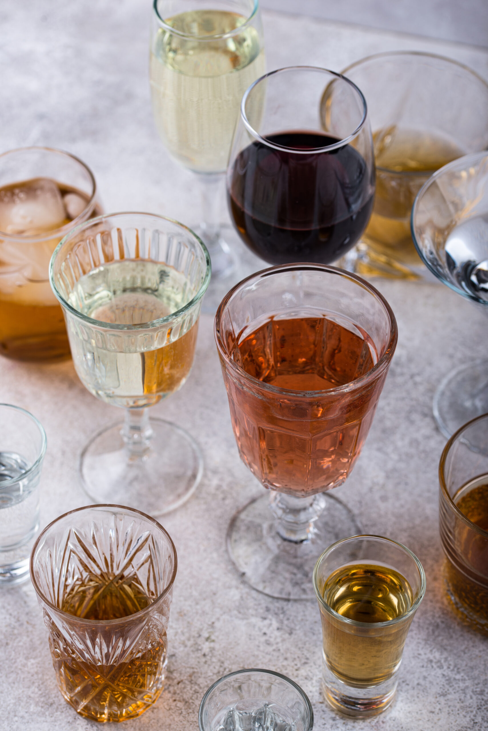 Ensemble de verres contenant différents types d’alcools, posés sur une table, illustrant la diversité des boissons consommées lors d’événements festifs.