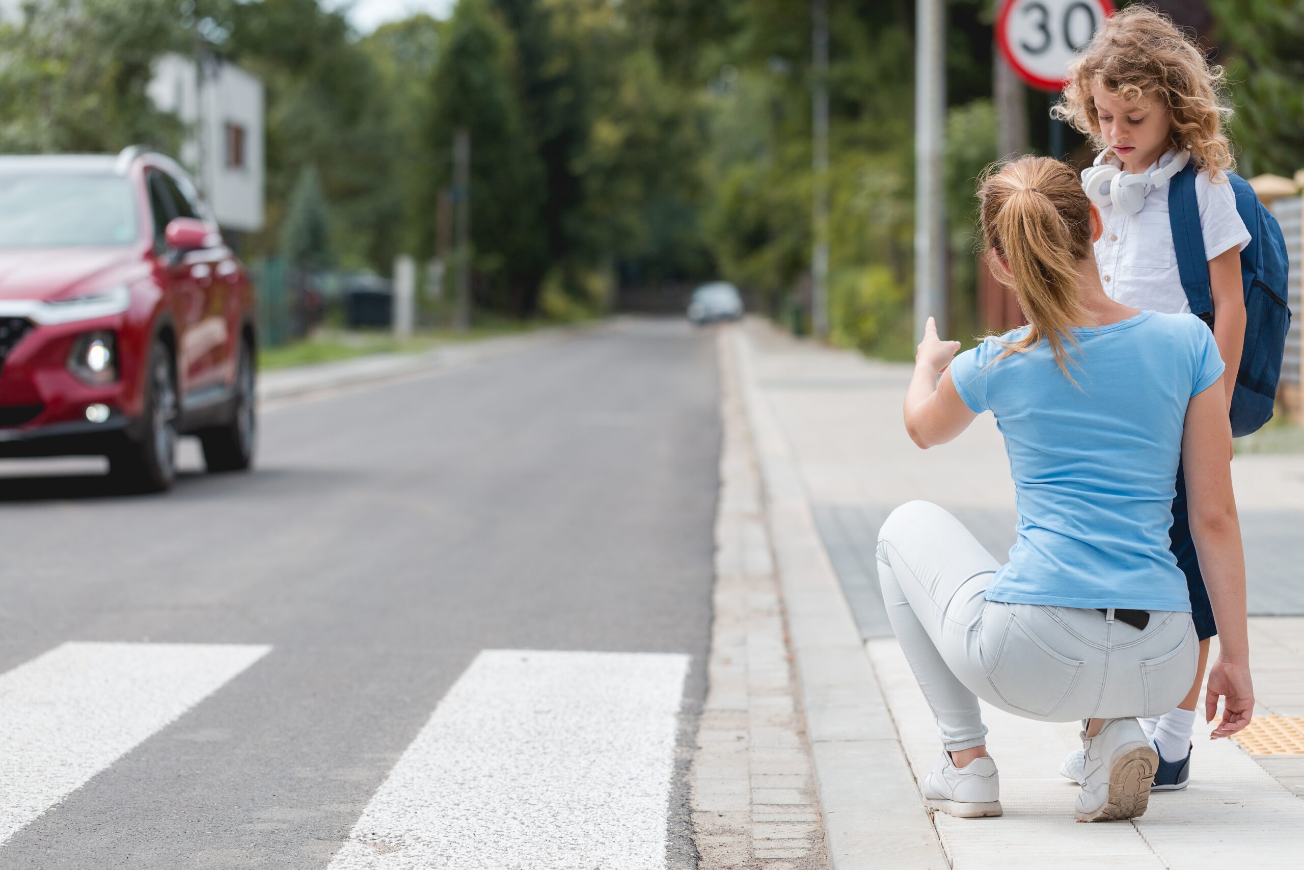 Prévention des accidents de la route : une mère montre à son enfant comment traverser en sécurité sur un passage piéton.