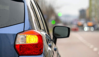 Voiture en circulation urbaine avec clignotant arrière activé pour signaler un changement de voie.
