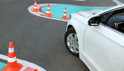Voiture circulant sur un parcours balisé avec des cônes de signalisation, illustrant un exercice de conduite sécurisée.