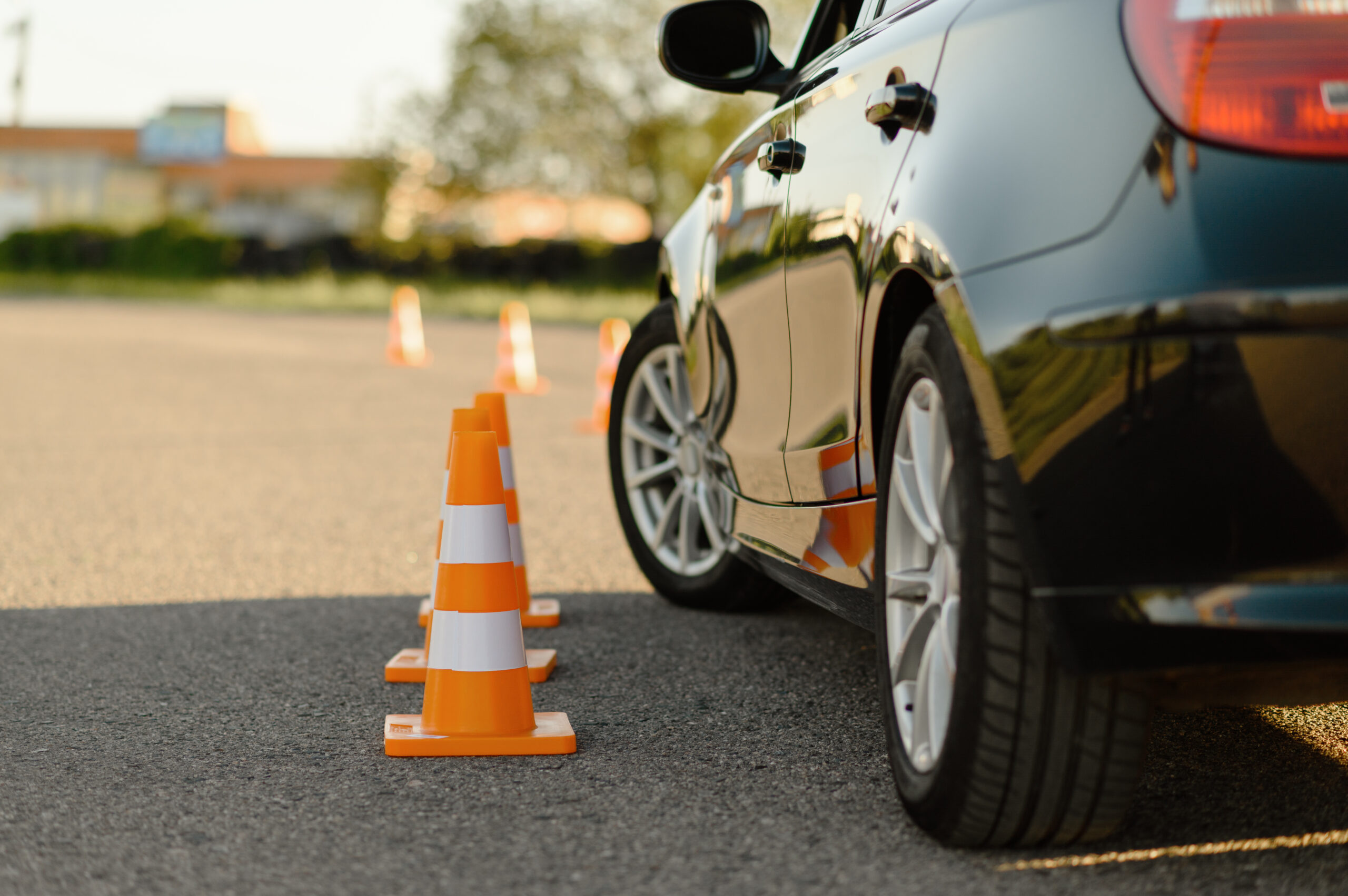 Voiture noire et cônes de signalisation orange sur un circuit d'entraînement pour la sécurité routière.