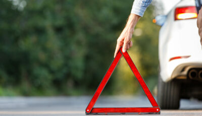 Conducteur posant un triangle de signalisation rouge derrière son véhicule après un accident de la route